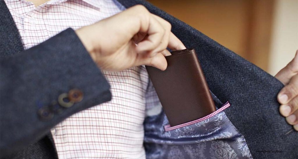 người đàn ông cầm ví da mỏng để vào túi áo